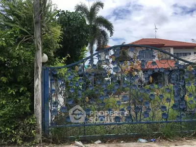 Charming suburban house with ornate blue gate and lush greenery