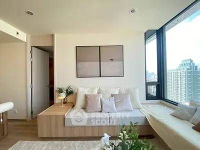Modern living room with large windows and city view, featuring cozy seating and stylish decor.