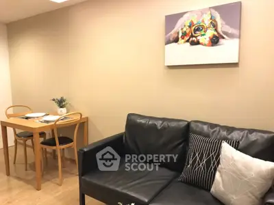 Cozy living room with black leather sofa and dining area, featuring modern decor and wall art.
