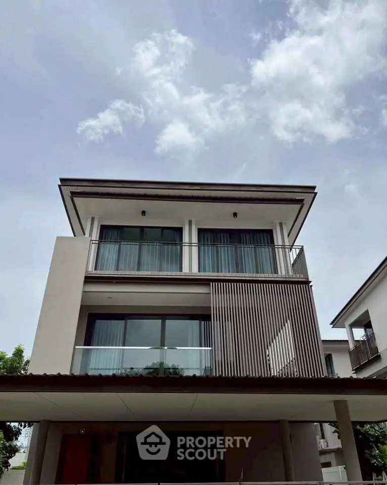 Modern three-story house with sleek design and large windows under a clear sky.