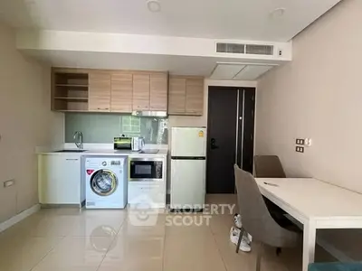 Modern kitchen with appliances including washing machine, fridge, and microwave in compact layout.