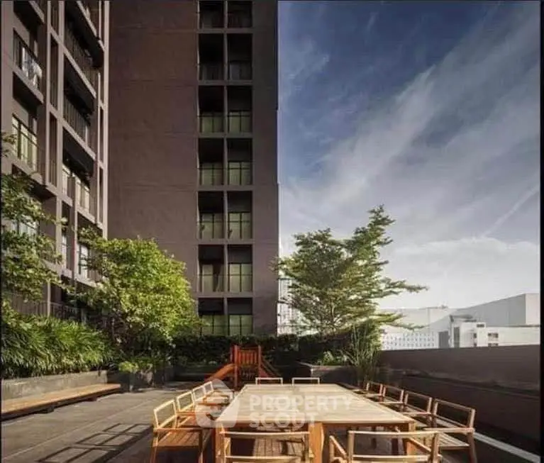 Modern building exterior with spacious outdoor seating area and lush greenery.