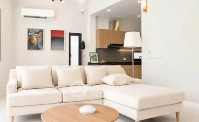 Modern living room with cozy beige sofa and open kitchen layout, perfect for stylish urban living.