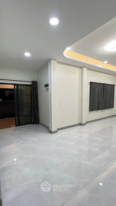 Spacious modern living room with sleek tile flooring and balcony access