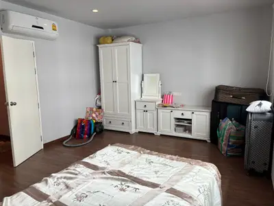 Spacious bedroom with wooden floor and white furniture, featuring ample storage space.