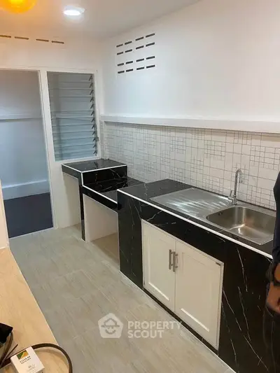 Modern kitchen with sleek black and white cabinetry and tiled backsplash