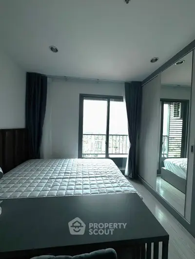 Modern bedroom with large window and mirrored wardrobe in a stylish apartment.