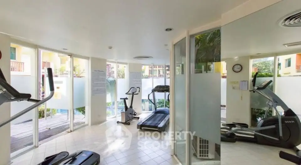 Modern gym with large windows and exercise equipment in a residential building.