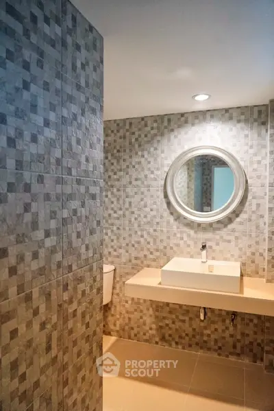 Modern bathroom with stylish tiled walls and round mirror