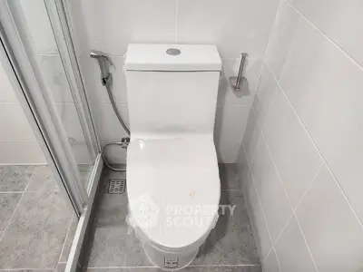 Modern bathroom with sleek toilet and shower area in contemporary design.