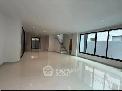 Spacious modern living room with large windows and glossy tiled floors in a contemporary home.