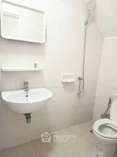 Modern minimalist bathroom with white fixtures and wall-mounted shower.