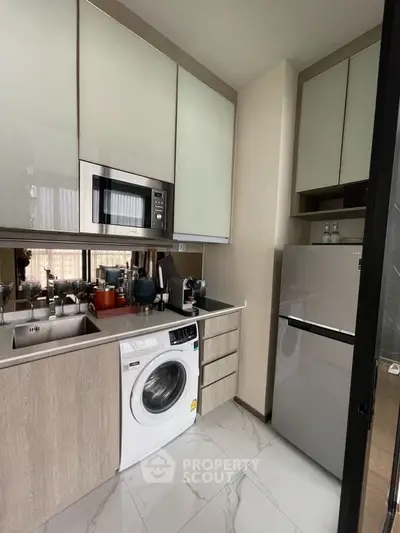 Modern kitchen with built-in appliances, washing machine, and sleek cabinetry.