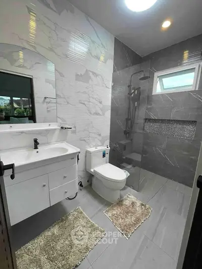 Modern bathroom with sleek design, featuring a glass shower and elegant fixtures.