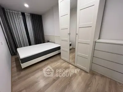 Modern minimalist bedroom with sleek wooden flooring and mirrored wardrobe