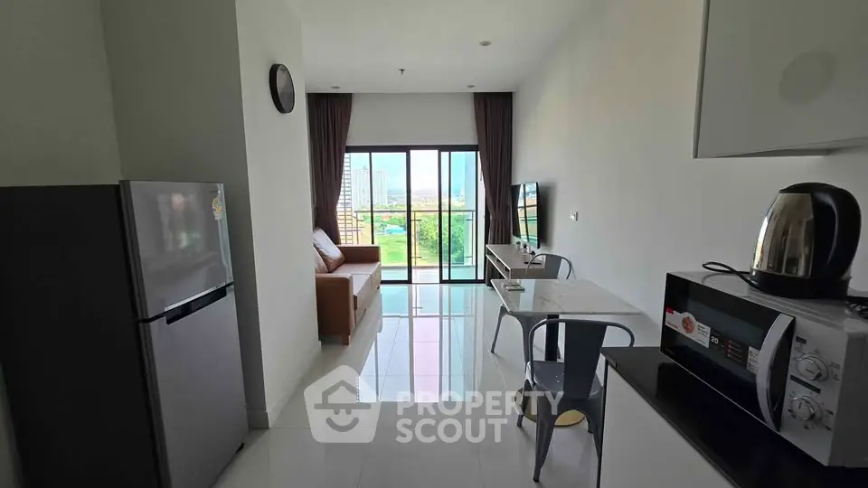 Modern apartment living room with balcony view and sleek kitchen appliances.