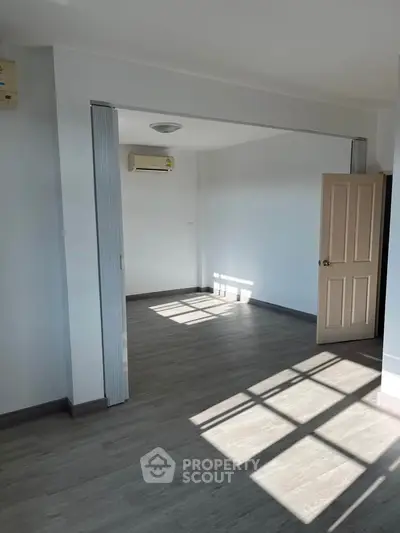 Spacious sunlit room with modern flooring and air conditioning, perfect for versatile living space.