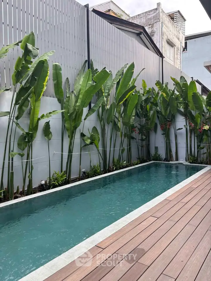 Luxurious private pool with tropical plants and modern decking in a serene outdoor setting.