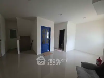 Spacious modern interior with glossy floors and unique blue door, ideal for creative living space.