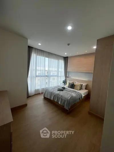 Spacious bedroom with large window and modern decor in a stylish apartment.