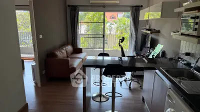 Modern open-plan living room with kitchen, featuring stylish furniture and large windows with a garden view.