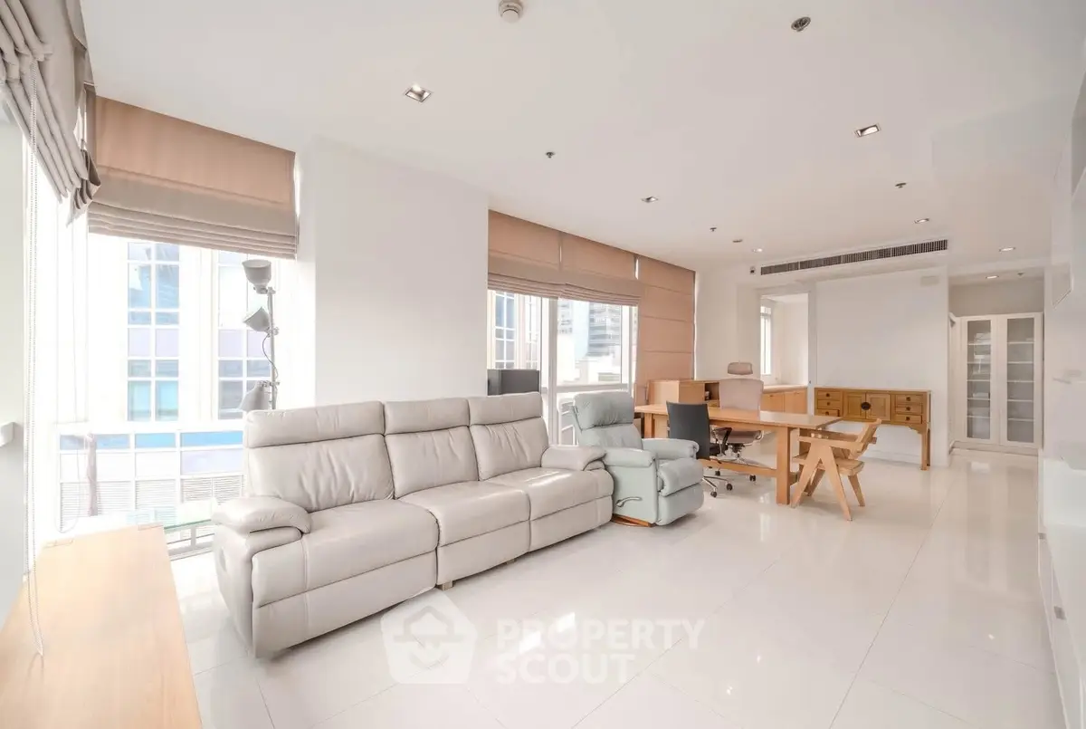 Spacious modern living room with sleek furniture and large windows in a high-rise apartment.