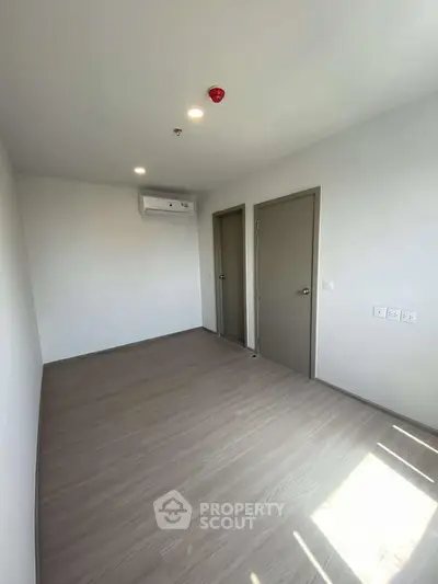 Spacious empty room with air conditioning and wooden flooring