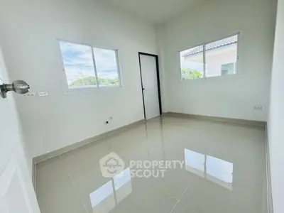 Bright empty room with glossy tiled floor and large windows in modern home.