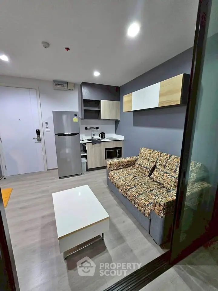 Modern living room with stylish sofa, sleek kitchen, and contemporary decor in a cozy apartment.