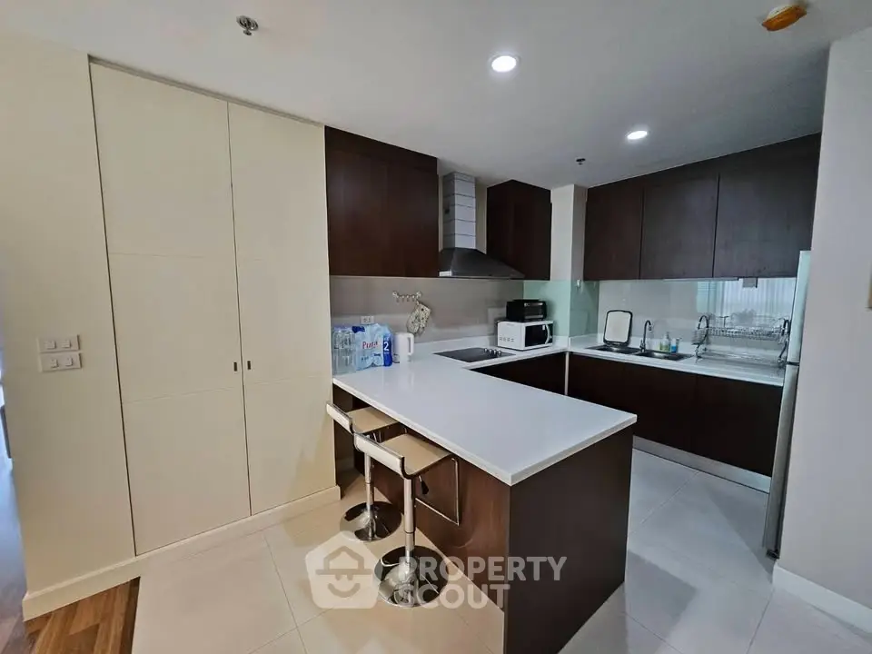 Modern kitchen with sleek cabinetry and island seating in a contemporary apartment.