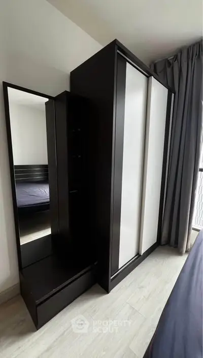 Modern bedroom with sleek wardrobe and full-length mirror, showcasing contemporary design and ample storage space.