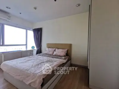 Cozy bedroom with large window and modern furnishings in a bright apartment.