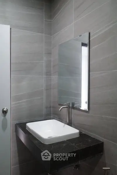 Modern bathroom with sleek sink and mirror in stylish gray tones.