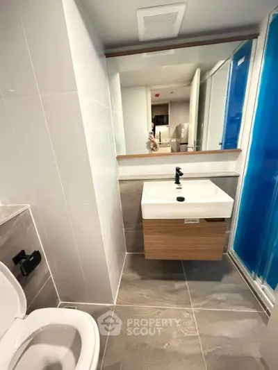 Modern bathroom with sleek fixtures and large mirror in contemporary apartment.