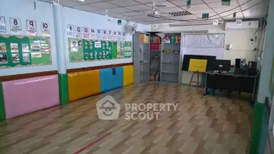 Spacious classroom with colorful wall decorations and wooden flooring, ideal for educational activities.