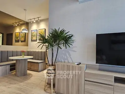 Modern living room with stylish furniture and large TV, featuring a cozy dining nook and decorative plant.
