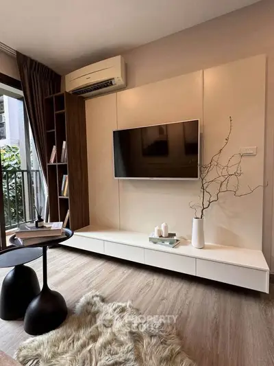 Modern living room with stylish decor, wall-mounted TV, and balcony view.