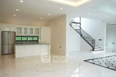 Spacious modern kitchen with sleek design and elegant staircase in luxury home