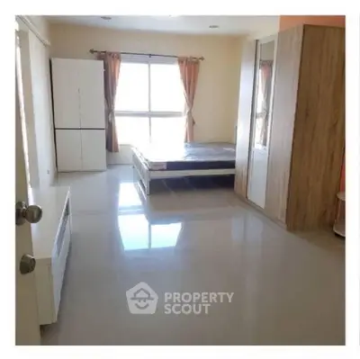 Spacious bedroom with large window and modern furnishings in a bright apartment.