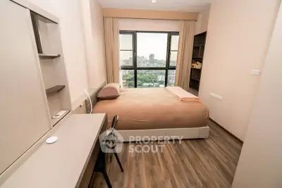 Modern bedroom with city view, featuring a cozy bed, desk, and large window for natural light.