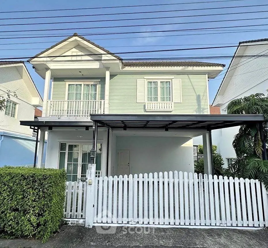 Charming two-story house with white picket fence and lush greenery, perfect for family living.