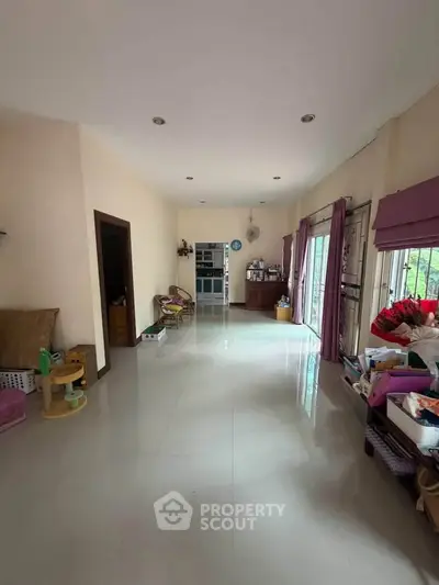 Spacious living room with large windows and natural light, perfect for family gatherings.