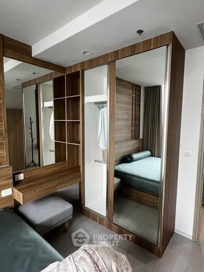Modern bedroom with mirrored wardrobe and wooden accents, featuring a cozy bed and stylish decor.