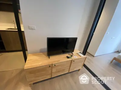 Modern living room with sleek wooden TV stand and open kitchen layout.