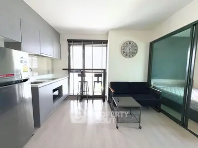 Modern studio apartment with sleek kitchen and cozy living area, featuring large windows and stylish decor.