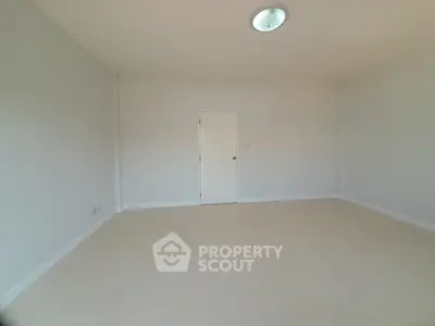 Spacious empty room with neutral walls and single door, ideal for customization.