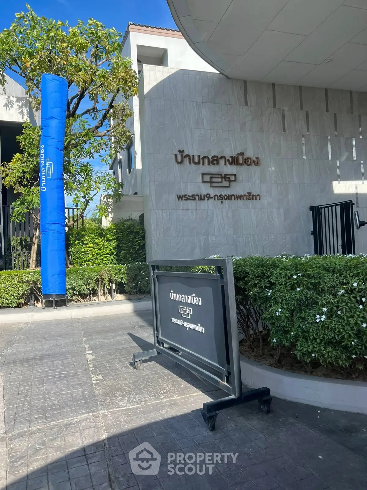 Modern building entrance with lush greenery and sleek signage