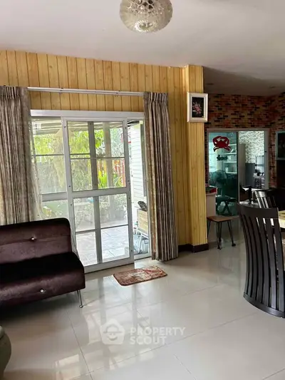 Charming living room with sliding glass doors leading to a lush garden, featuring modern decor and elegant dining area.