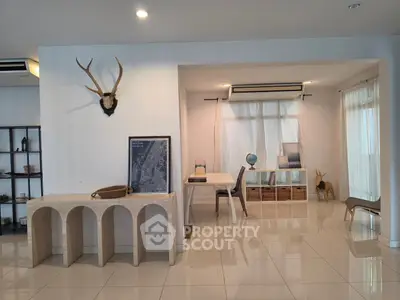 Modern living room with stylish decor and natural light, featuring a unique antler wall piece and elegant furniture.