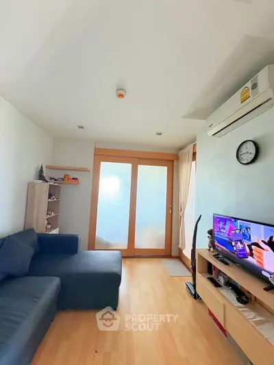 Cozy living room with modern decor and wooden flooring, featuring a comfortable sofa and entertainment setup.